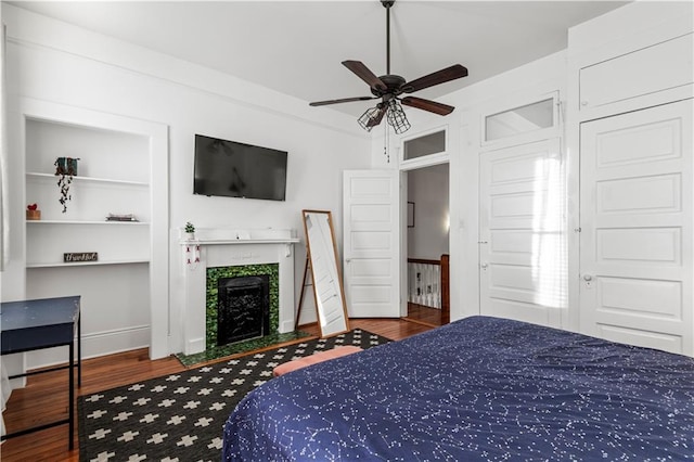 bedroom featuring a tile fireplace, wood-type flooring, and ceiling fan