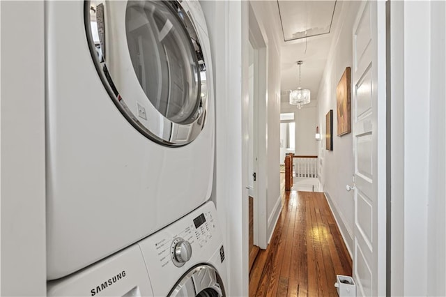 laundry area with stacked washer / dryer, dark hardwood / wood-style flooring, and a chandelier