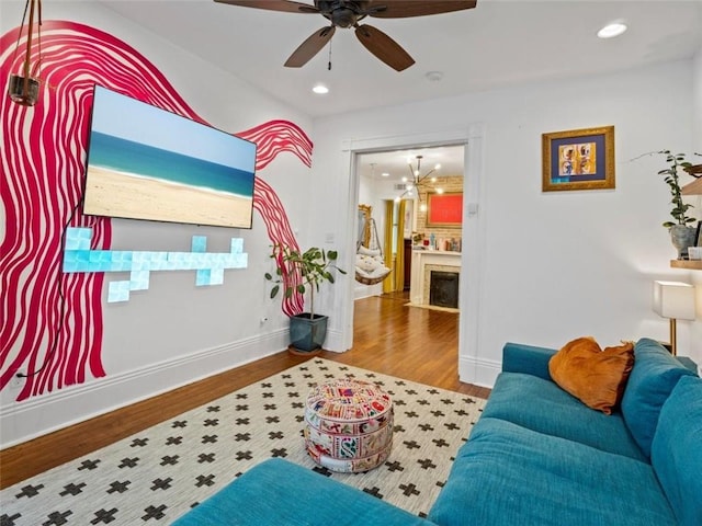 living room with wood-type flooring and ceiling fan with notable chandelier