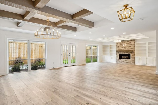 unfurnished living room with beam ceiling, coffered ceiling, an inviting chandelier, a brick fireplace, and light hardwood / wood-style floors