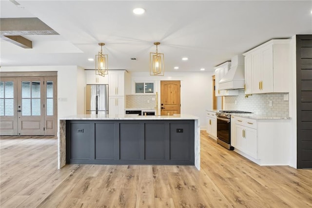 kitchen featuring custom exhaust hood, stainless steel appliances, pendant lighting, white cabinets, and a large island