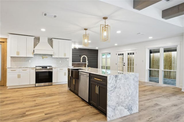2914 Ridgeway Dr, Metairie, LA 70002 - kitchen featuring stainless steel appliances, premium range hood, white cabinetry, light wood finished floors, and recessed lighting