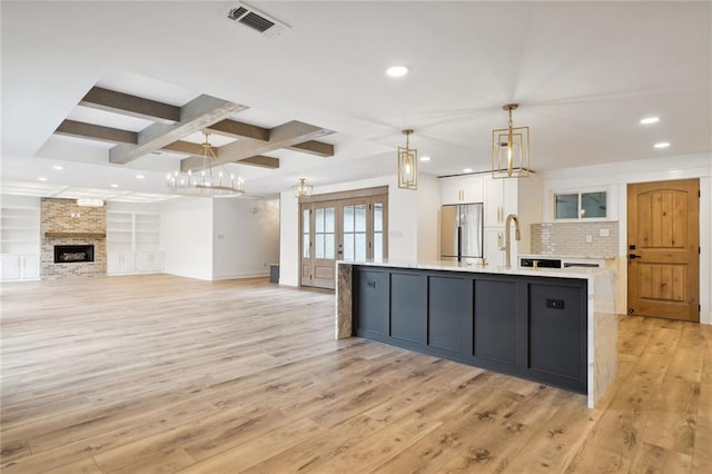 2914 Ridgeway Dr, Metairie, LA 70002 - kitchen with stainless steel fridge, white cabinets, light wood finished floors, light countertops, and a chandelier