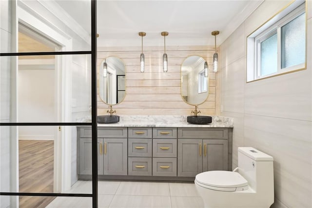 bathroom featuring tile patterned floors, vanity, toilet, and wooden walls