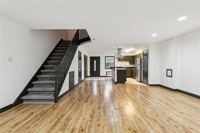 kitchen featuring stainless steel refrigerator, a center island, light hardwood / wood-style floors, and island exhaust hood