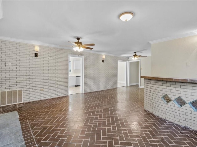 unfurnished living room with ceiling fan, brick wall, and ornamental molding