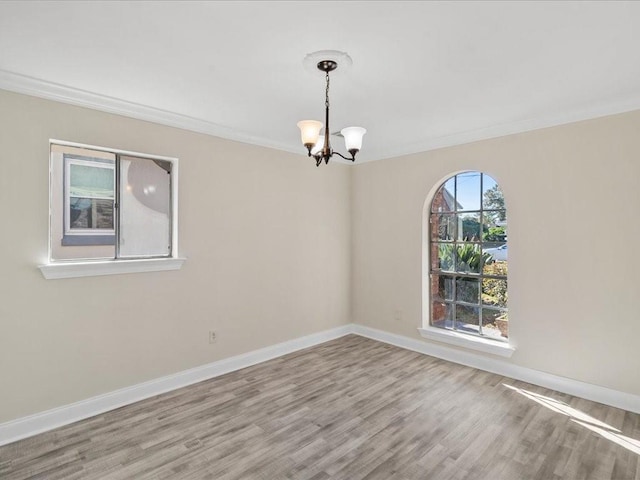 spare room featuring hardwood / wood-style floors, an inviting chandelier, and ornamental molding