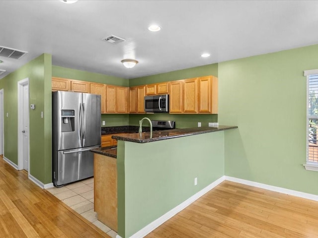 kitchen featuring light hardwood / wood-style floors, kitchen peninsula, and appliances with stainless steel finishes