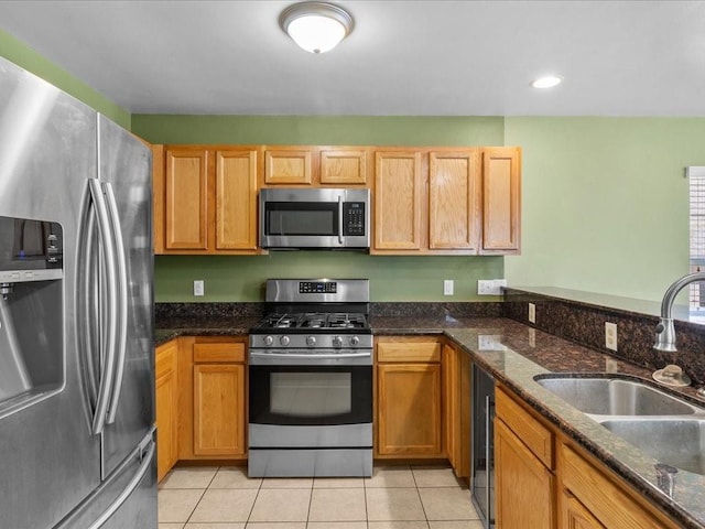 kitchen featuring light tile patterned flooring, dark stone countertops, sink, and appliances with stainless steel finishes