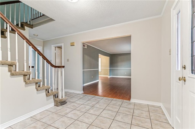 tiled entryway featuring crown molding and a textured ceiling