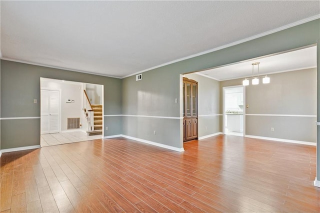 empty room with ornamental molding, a chandelier, and light wood-type flooring