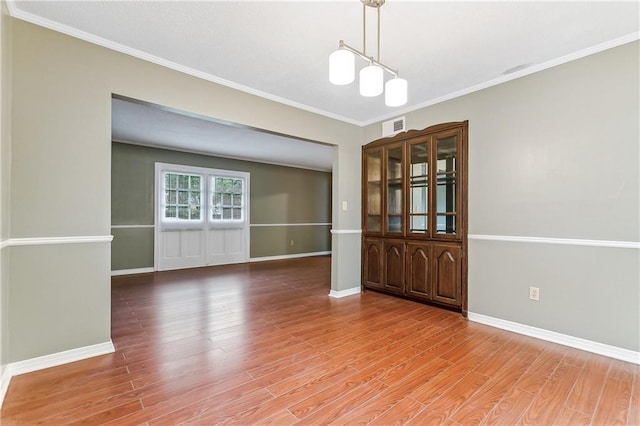 unfurnished dining area featuring an inviting chandelier, hardwood / wood-style flooring, and ornamental molding