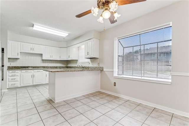 kitchen with backsplash, light tile patterned floors, kitchen peninsula, and white cabinets