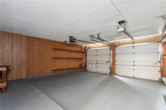 garage featuring a garage door opener and wood walls