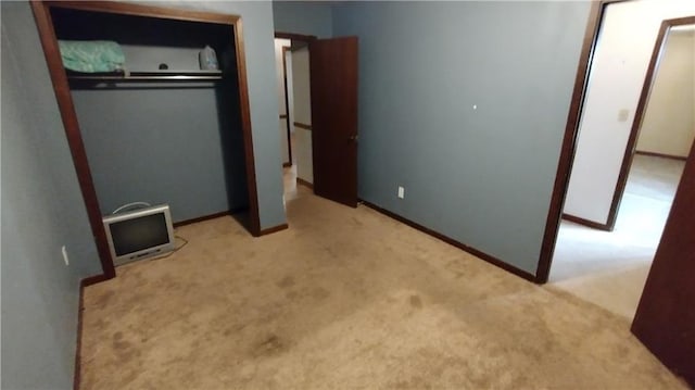 unfurnished bedroom featuring light carpet and a closet