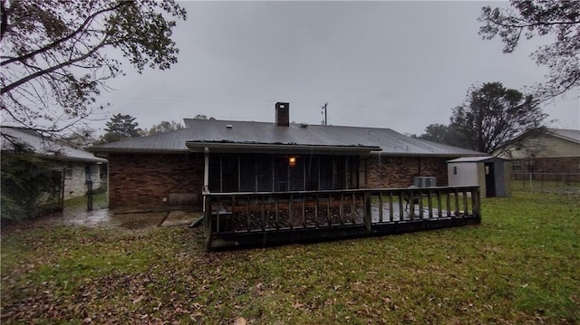 back of house with a wooden deck, cooling unit, a sunroom, a shed, and a lawn