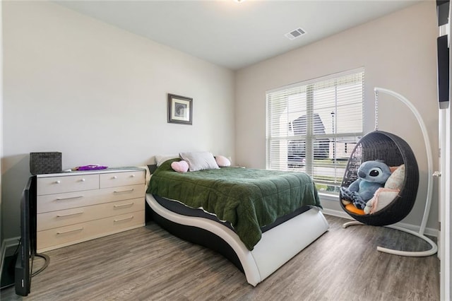 bedroom with multiple windows and dark hardwood / wood-style flooring