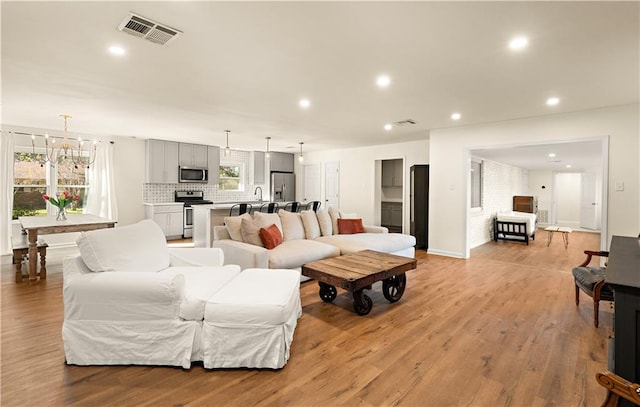 living room with light hardwood / wood-style flooring, a notable chandelier, and sink