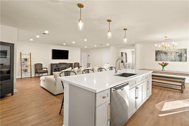 kitchen featuring pendant lighting, dishwasher, sink, and a kitchen island with sink