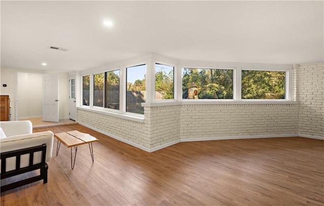 interior space featuring hardwood / wood-style flooring, plenty of natural light, and brick wall