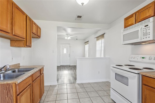 kitchen featuring light tile patterned flooring, white appliances, ceiling fan, and sink