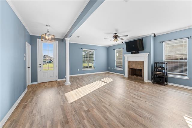 entryway with ceiling fan with notable chandelier, hardwood / wood-style flooring, ornate columns, and ornamental molding