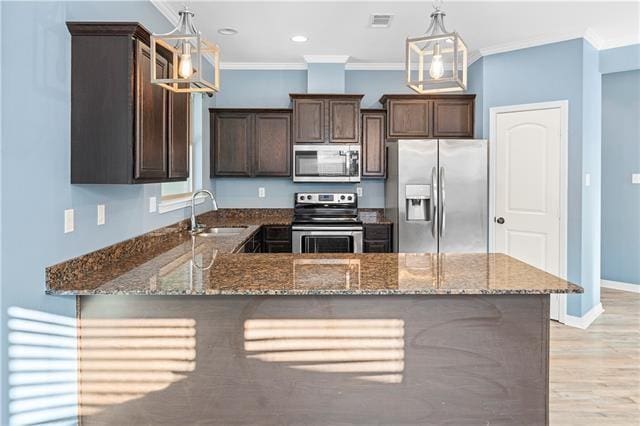 kitchen featuring decorative light fixtures, sink, stainless steel appliances, and dark stone counters