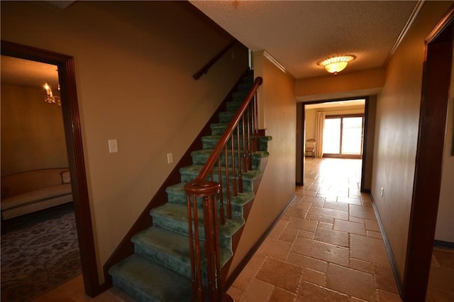 staircase featuring ornamental molding and a textured ceiling