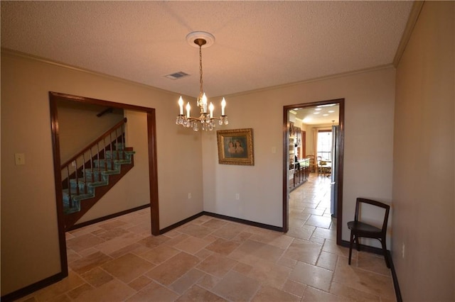 unfurnished dining area featuring a textured ceiling, ornamental molding, and a notable chandelier