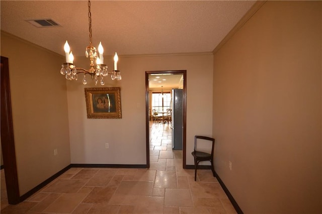 unfurnished dining area featuring ornamental molding, a textured ceiling, and a chandelier