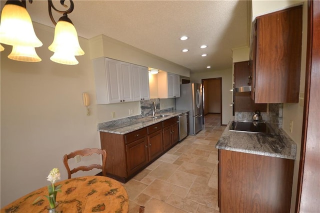 kitchen featuring decorative light fixtures, light stone counters, sink, and appliances with stainless steel finishes