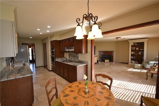 kitchen featuring appliances with stainless steel finishes, dark brown cabinetry, ventilation hood, decorative light fixtures, and a notable chandelier