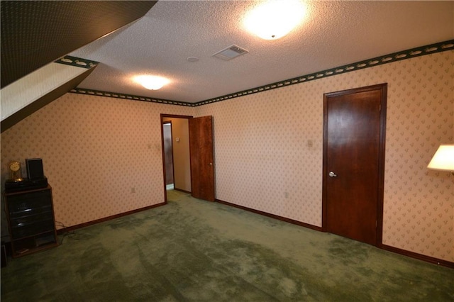 unfurnished bedroom with a textured ceiling and dark colored carpet