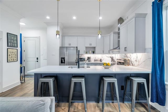 kitchen with appliances with stainless steel finishes, a kitchen breakfast bar, decorative light fixtures, hardwood / wood-style flooring, and white cabinets