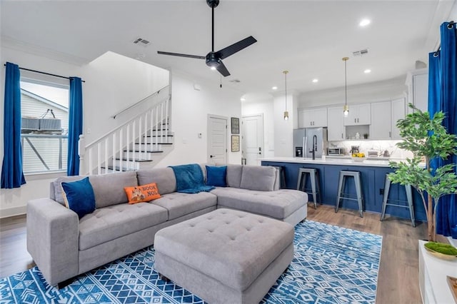 living room featuring hardwood / wood-style floors, ceiling fan, and ornamental molding