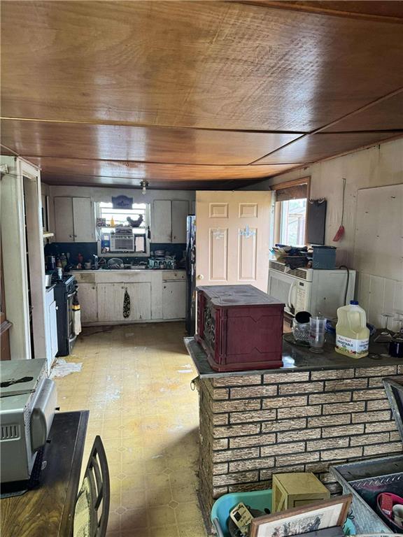 kitchen with stainless steel range oven, fridge, wooden walls, and wood ceiling