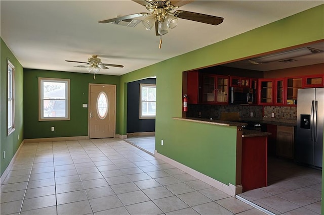 interior space with a wealth of natural light, light tile patterned flooring, appliances with stainless steel finishes, and tasteful backsplash