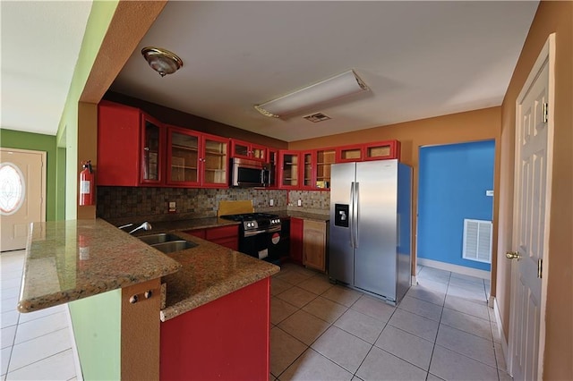 kitchen with sink, tasteful backsplash, kitchen peninsula, light tile patterned floors, and appliances with stainless steel finishes