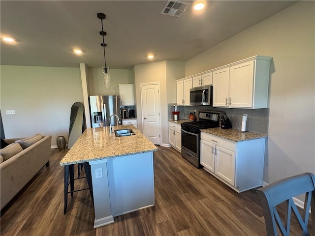 kitchen with visible vents, dark wood-style flooring, a sink, stainless steel appliances, and backsplash