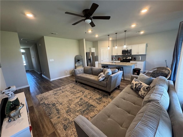 living room featuring a ceiling fan, visible vents, baseboards, recessed lighting, and dark wood-type flooring