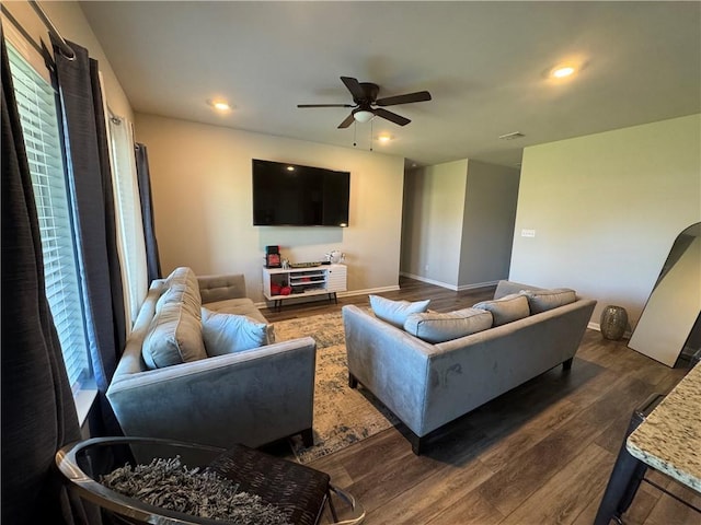 living area featuring a ceiling fan, visible vents, baseboards, dark wood finished floors, and recessed lighting