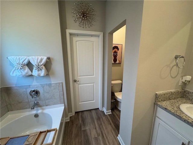 full bath with baseboards, toilet, a garden tub, wood finished floors, and vanity