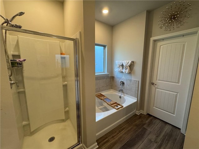 bathroom with a garden tub, wood finished floors, and a stall shower