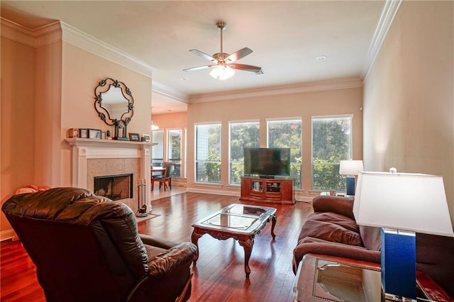 living room featuring ceiling fan, a fireplace, wood-type flooring, and ornamental molding