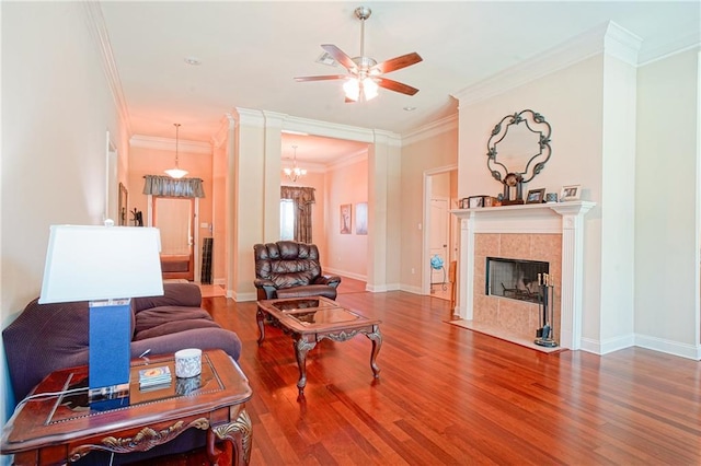 living room featuring a fireplace, hardwood / wood-style floors, ceiling fan with notable chandelier, and ornamental molding