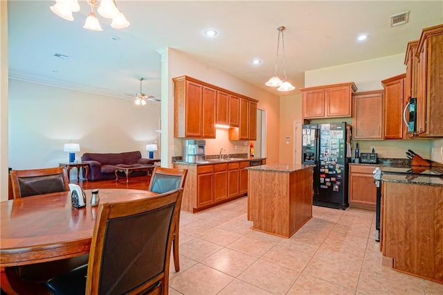 kitchen featuring black fridge with ice dispenser, a center island, light tile patterned floors, and dark stone counters