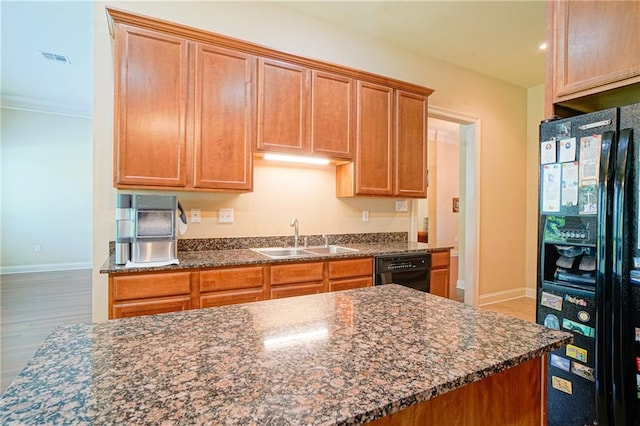 kitchen featuring hardwood / wood-style floors, dark stone countertops, sink, and black appliances