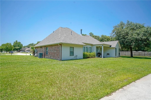 rear view of house featuring a lawn and central AC