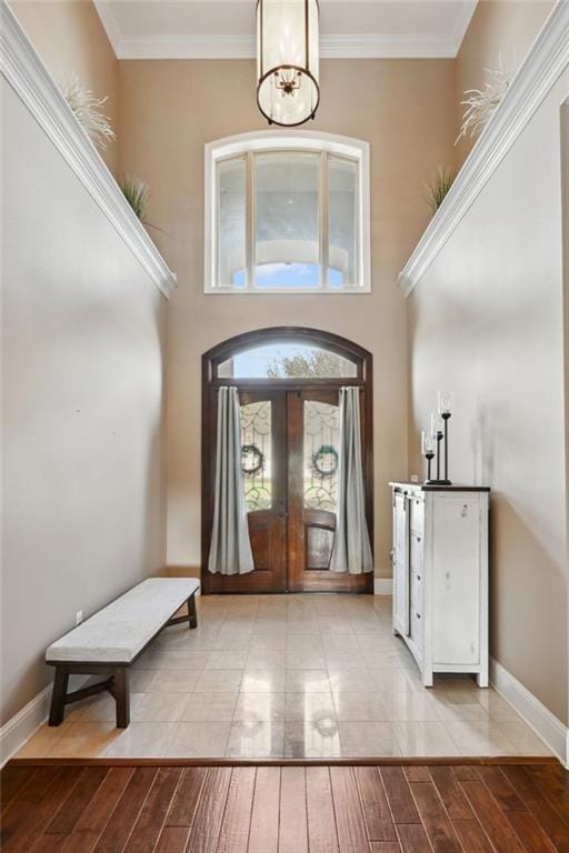 foyer featuring a notable chandelier, ornamental molding, light wood-type flooring, and french doors