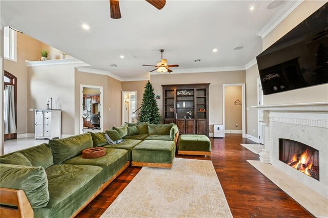 living room featuring ceiling fan, a premium fireplace, crown molding, and dark hardwood / wood-style floors